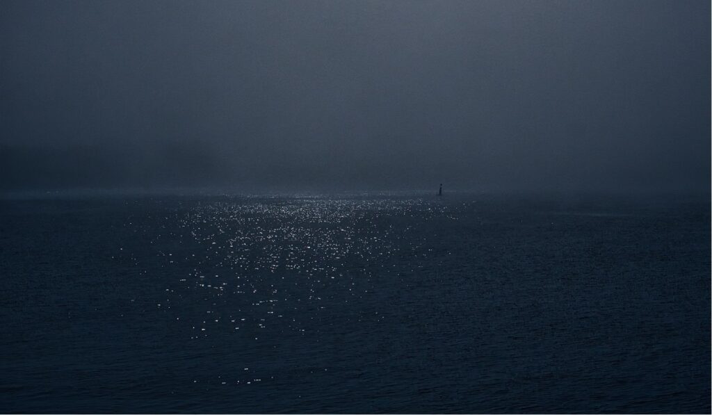 «Drift», liminal image: fishing net, splintered wood, and a golden thermal blanket in half-light.