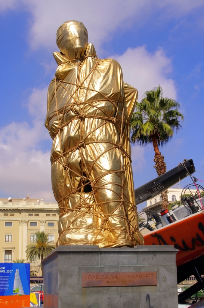 Monumento al poeta Joan Salvat-Papasseit envuelto en manta térmica dorada de rescate, cuerda y nudos marineros.